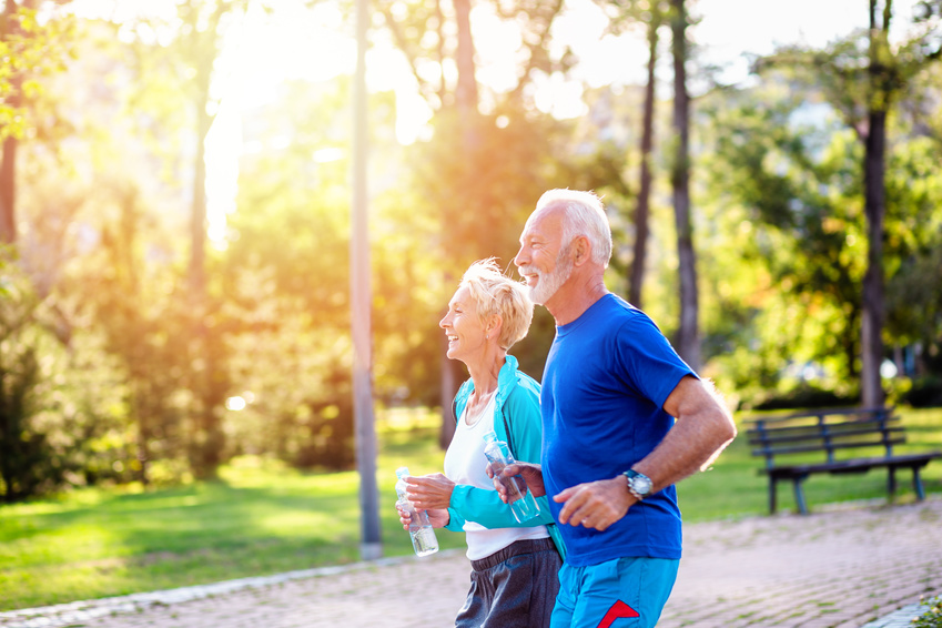 Happy senior couple jogging outdoors in park. Running after 65